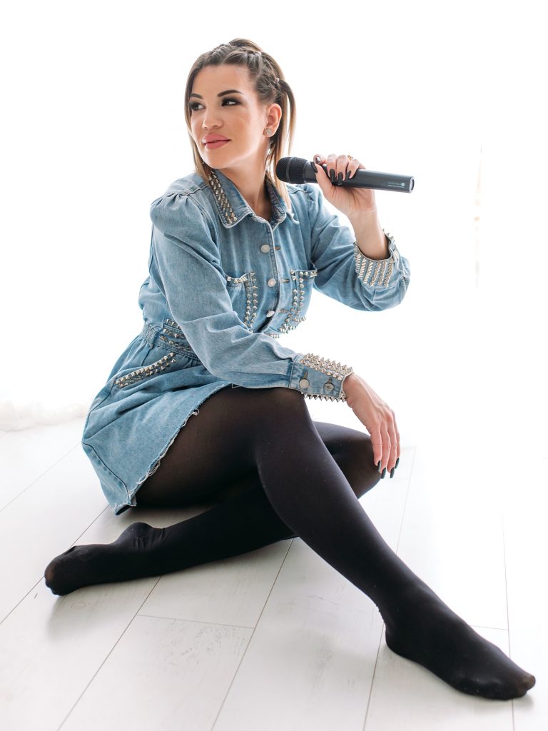 KLAU énekesnő és retro DJ mikrofonnal, farmer ruhában, világos stúdióban
