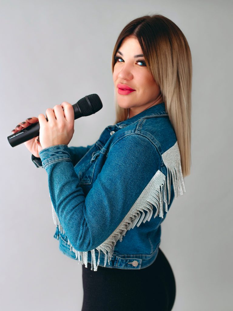 KLAU énekesnő és retro DJ mikrofonnal, farmer kabárban, világos stúdióban